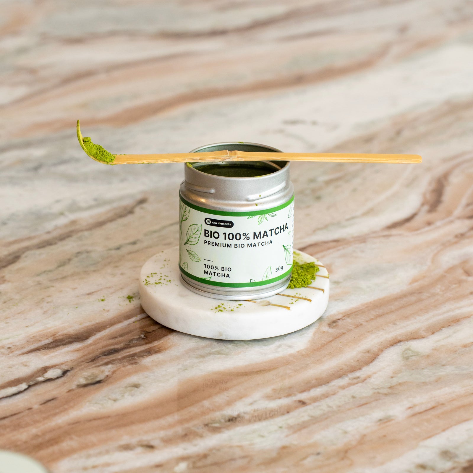 Chashaku Matcha-Löffel aus Goldbambus auf einem runden Marmor-Untersetzer mit Matcha-Pulver