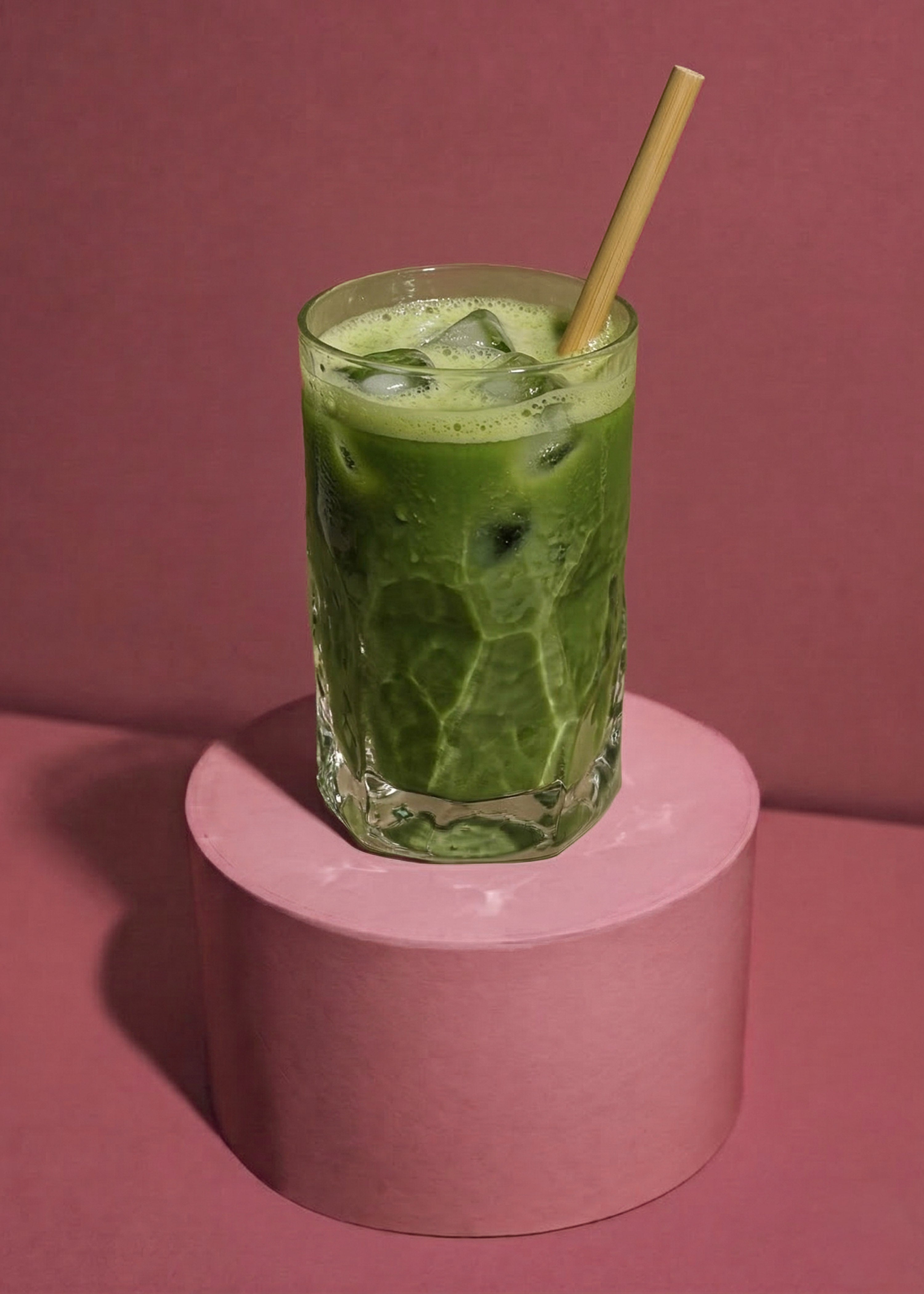 Gekühltes Glas eines veganen Iced Erdbeer Matcha Latte mit Pflanzenmilch, garniert mit einer frischen Erdbeere