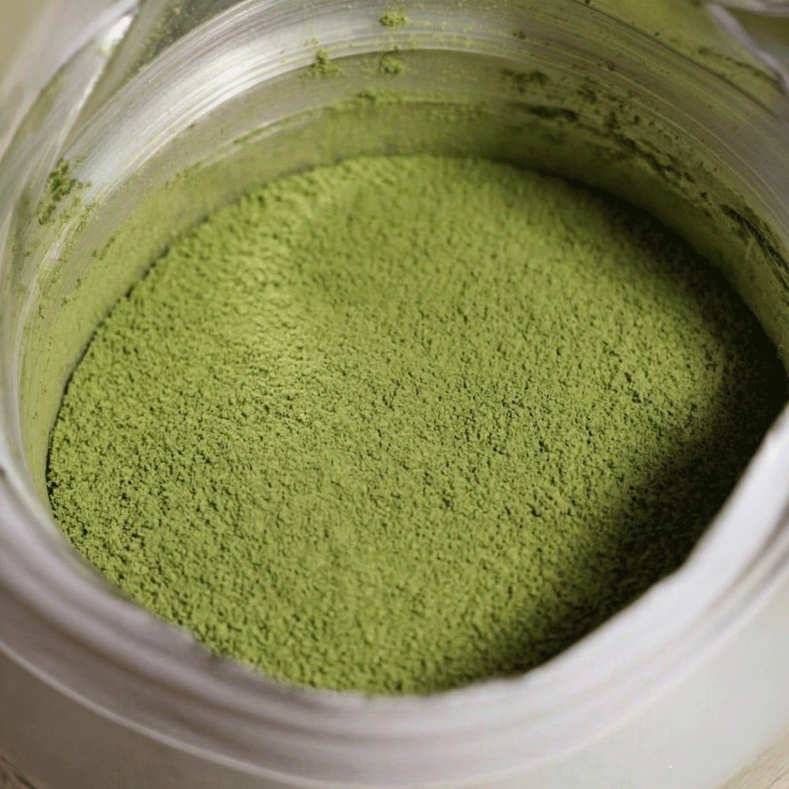 Detaillierte Nahaufnahme von feingemahlenem, leuchtend grünem Premium Mango Matcha Pulver im Inneren der Verpackung.