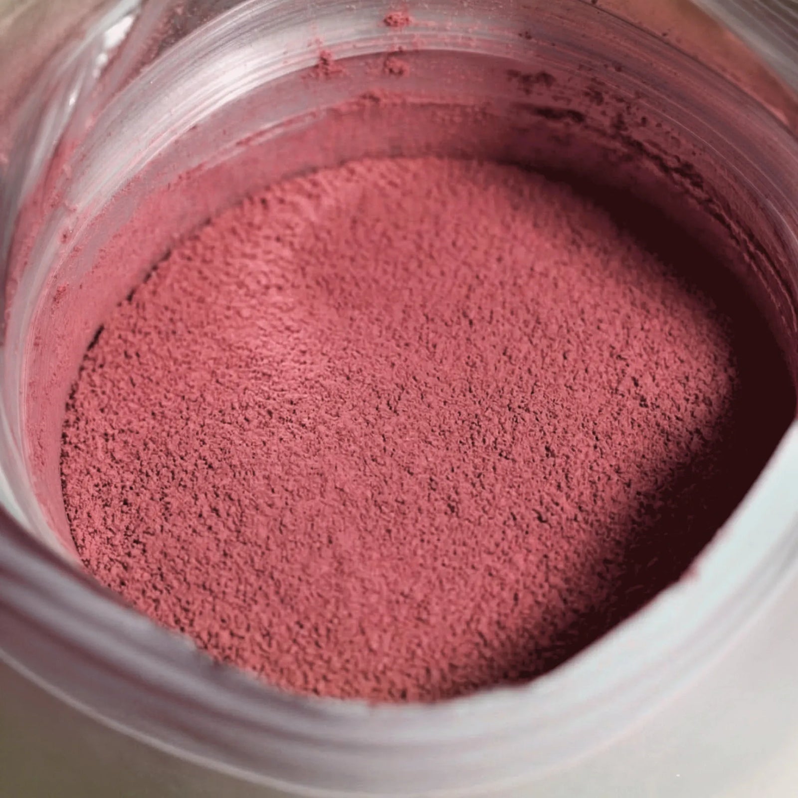 Nahaufnahme von fein gemahlenem Raw Elements Bio Acai Beeren Pulver in kräftigem Rosa in der geöffneten Dose