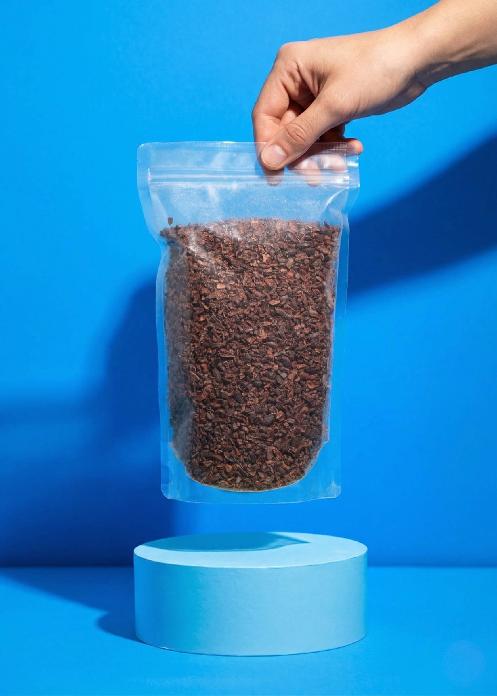 Eine Hand hält den 500g Beutel Bio Kakaonibs, ideal als gesundes Topping für Bowls, Müsli oder zum Backen