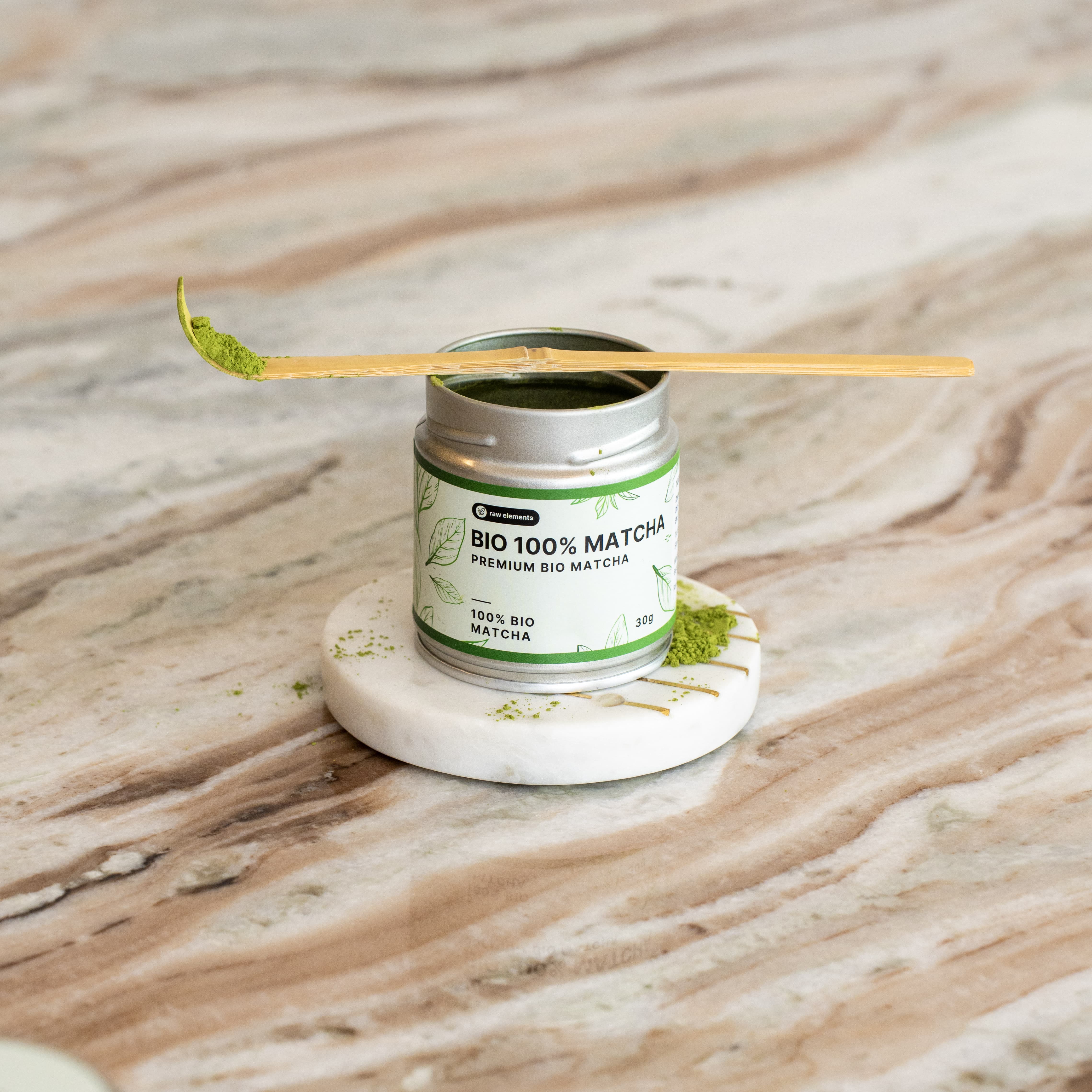 Chashaku Matcha-Löffel aus Goldbambus auf einem runden Marmor-Untersetzer mit Matcha-Pulver