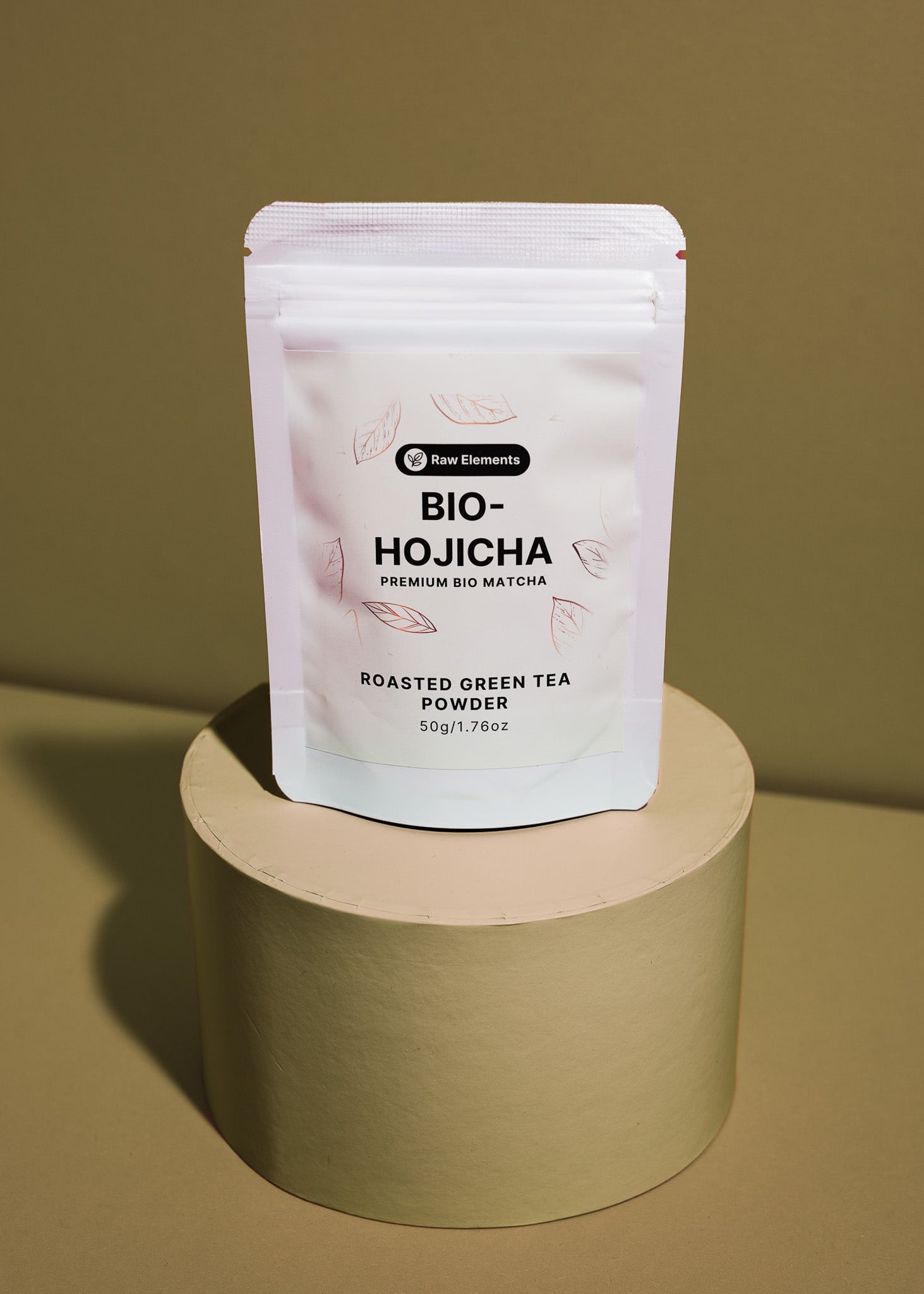 Standbodenbeutel mit Bio Hojicha Pulver neben feinem, braunem Röstgrüntee auf einem Holzlöffel.