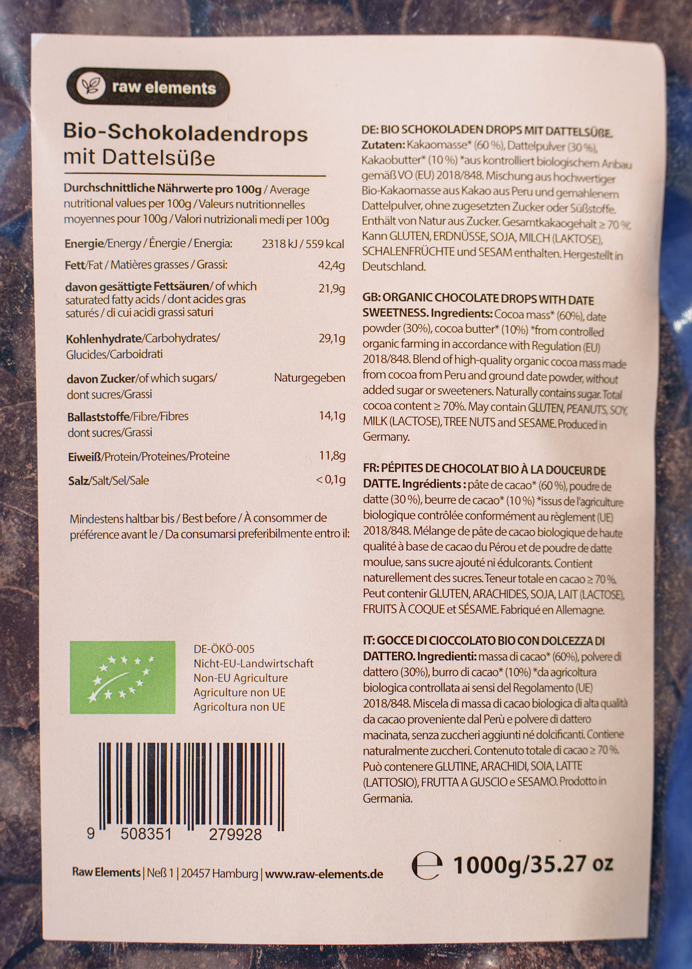 Rückseite des 1kg-Beutels der Raw Elements Bio-Schokoladendrops mit Dattelsüße. Das Etikett zeigt die detaillierte Zutatenliste, Nährwerttabelle und das Bio-Siegel in Deutsch, Englisch, Französisch und Italienisch
