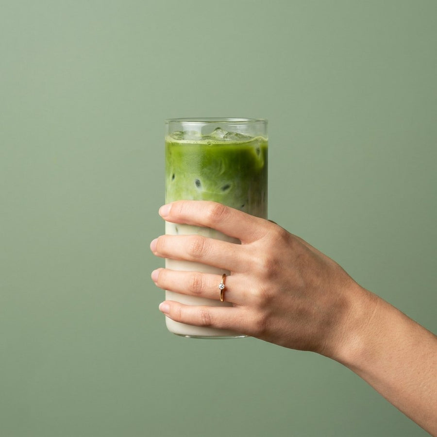 Hand hält ein Glas Iced Matcha Latte